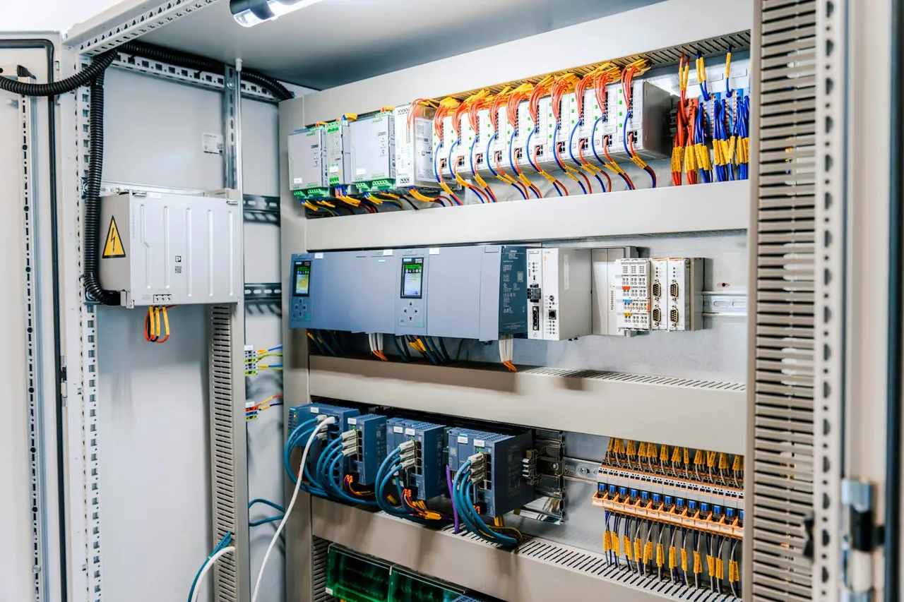 Armario eléctrico abierto con PLC, protecciones y cableado ordenado